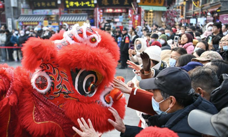 People interact with a lion dancer at an ancient cultural street in north China's Tianjin Municipality, Jan. 1, 2025. People across China enjoy themselves in various activities, celebrating the first day of 2025. (Xinhua/Sun Fanyue)