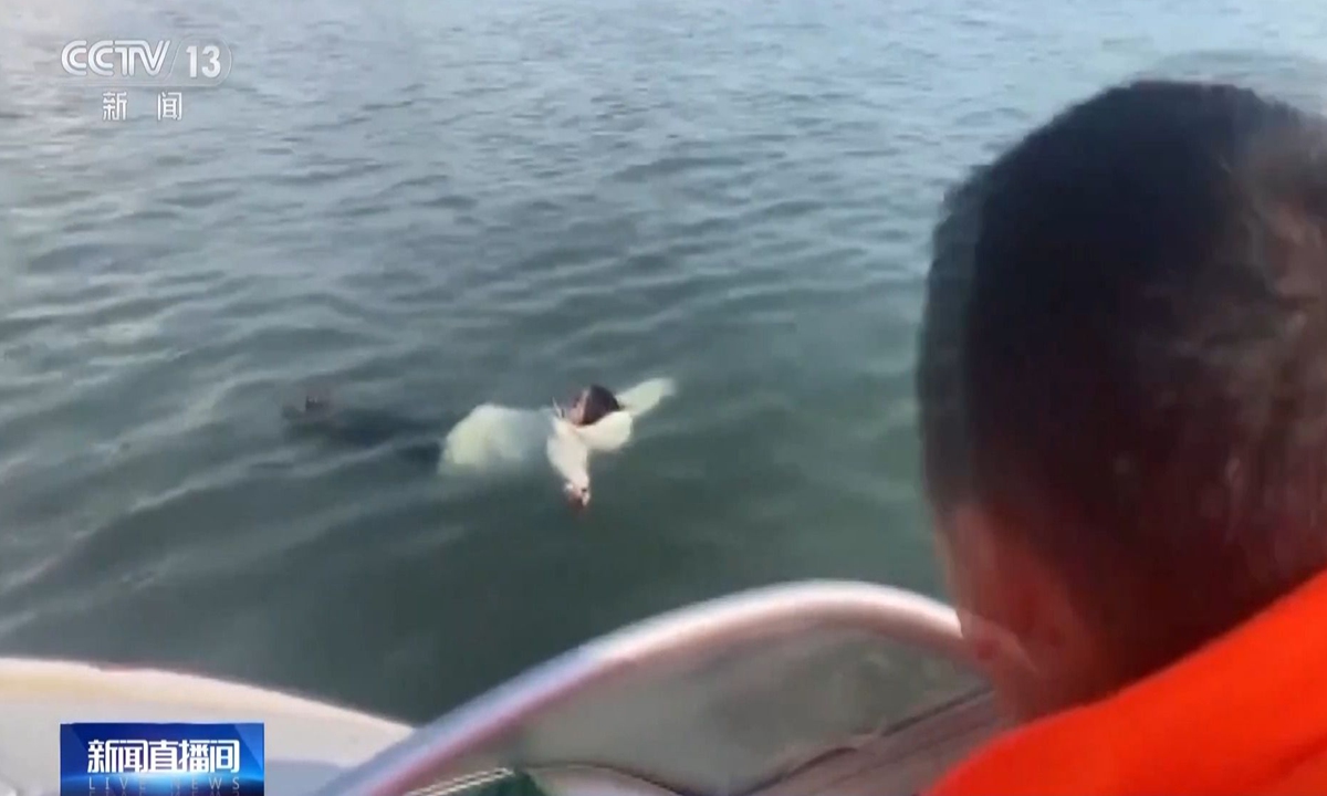 A bystander spots a woman floating on the water in Qingdao, East China's Shandong Province. Photo: screenshot of CCTV