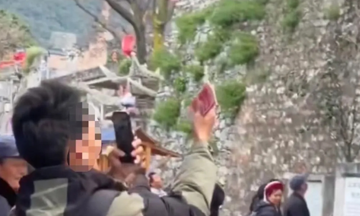 A person holds cash as a Chinese man from Dali, Southwest China's Yunnan Province caught scattering cash over ancient walls. Photo: screenshot