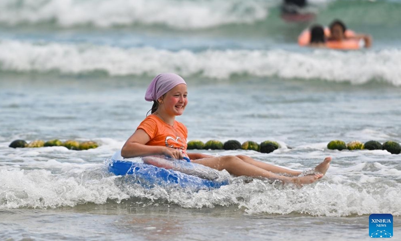 An overseas tourist enjoys herself at the Dadonghai scenic area in Sanya City, south China's Hainan Province, Aug. 28, 2024.