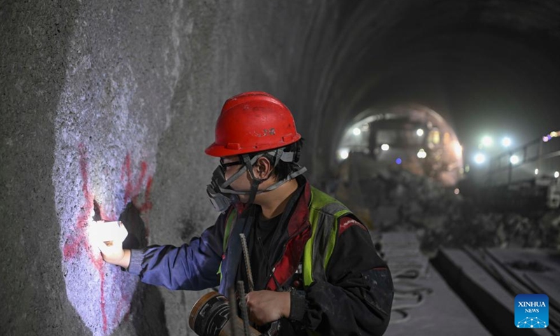 A worker takes measurements at the construction site of Tianshan Shengli tunnel along the expressway linking Urumqi and Yuli County in northwest China's Xinjiang Uygur Autonomous Region, Dec. 25, 2024. (Xinhua/Hu Huhu)