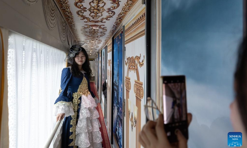 A dressed-up passenger poses for photos on the train K5197 in northeast China's Heilongjiang Province, Jan. 2, 2025. The train K5197 from Harbin to Yabuli South of northeast China's Heilongjiang Province, the first train themed on ice and snow tourism under the China Railway Harbin Group, started operation on Thursday. Passengers can experience photo taking in cabinets with different themes. (Xinhua/Zhang Tao)