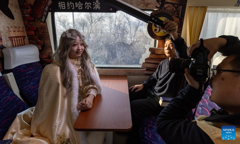 A dressed-up passenger poses for photos on the train K5197 in northeast China's Heilongjiang Province, Jan. 2, 2025. The train K5197 from Harbin to Yabuli South of northeast China's Heilongjiang Province, the first train themed on ice and snow tourism under the China Railway Harbin Group, started operation on Thursday. Passengers can experience photo taking in cabinets with different themes. (Xinhua/Zhang Tao)