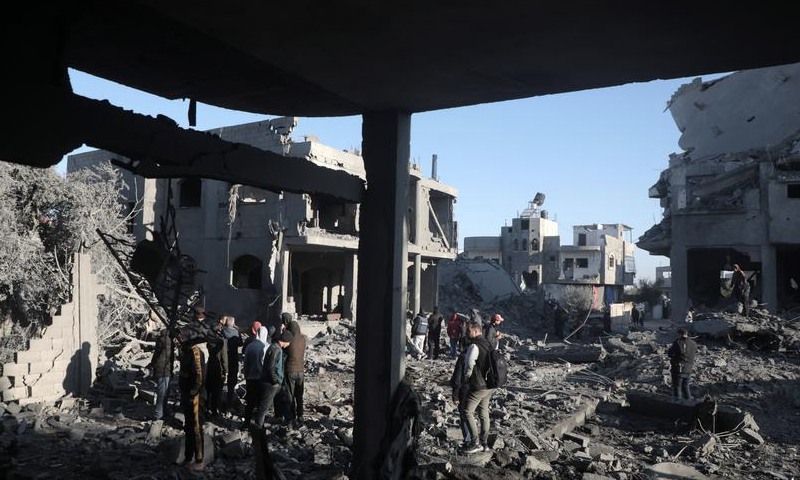 People gather near buildings destroyed after Israeli bombardment in the Maghazi refugee camp, central Gaza Strip, on Jan. 3, 2025. (Photo by Rizek Abdeljawad/Xinhua)