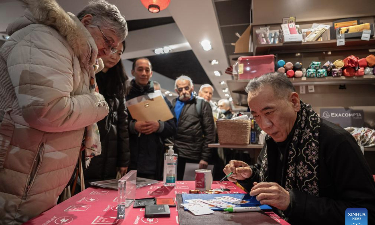 Chen Jianghong (R), a French artist of Chinese origin, also the designer of the stamps, signs on the Year of the Snake commemorative stamps during a launching ceremony in Paris, France, Jan. 18, 2025. French post office, La Poste, on Saturday issued two stamps to celebrate the upcoming Chinese New Year, the Year of the Snake, which starts on Jan. 29, 2025. (Photo by Aurelien Morissard/Xinhua)