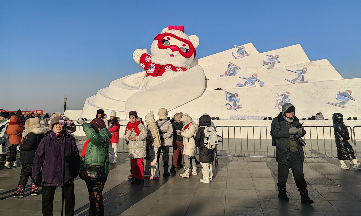 Tourists take photos in front of the snow sculpture of Nini, one of the two mascots of the Asian Winter Games, in Harbin, Northeast China's Heilongjiang Province, on December 27, 2024. Photo: VCG