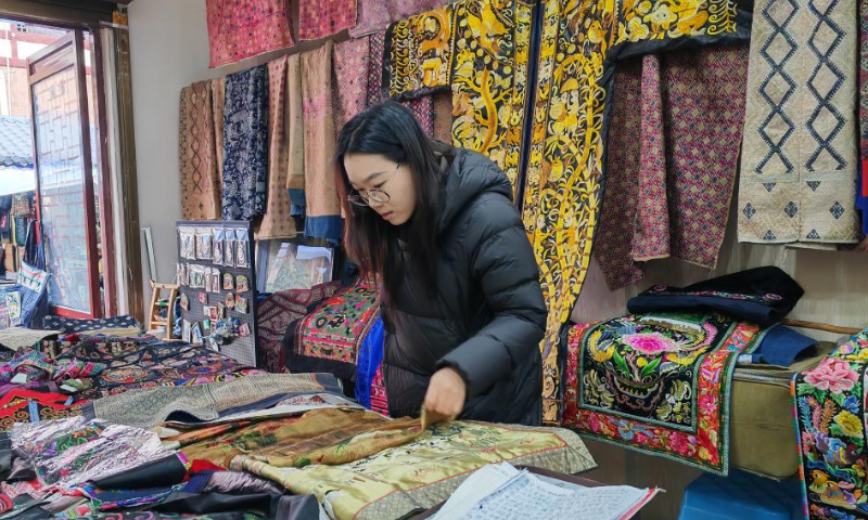 A visitor selects artworks at an intangible heritage market in the city of Kaili in Qiandongnan Miao and Dong Autonomous Prefecture in southwest China's Guizhou Province, Jan. 9, 2025. (Xinhua/Wu Si)