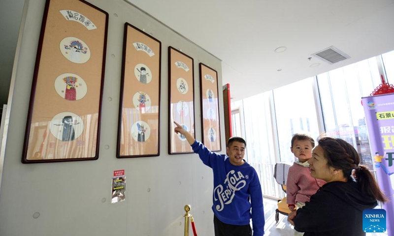 Yang Qiang (L) introduces Peking Opera facial makeup painting at a cultural center in Shijingshan District in Beijing, capital of China, Jan. 8, 2025. (Xinhua/Li Xin)