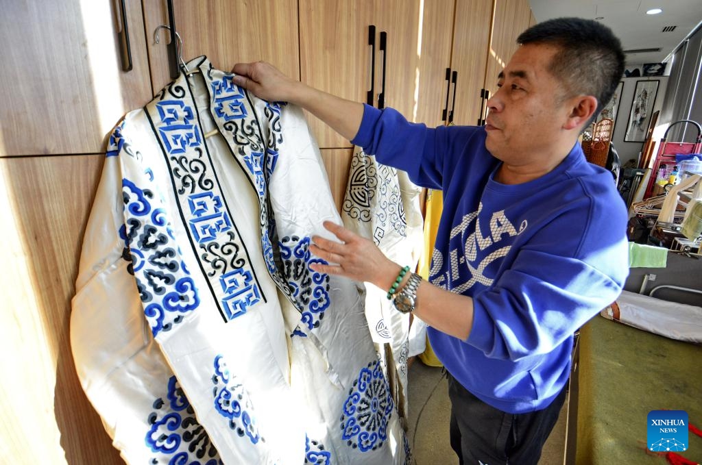 Yang Qiang arranges the attire for Peking Opera performance in Beijing, capital of China, Jan. 8, 2025. (Xinhua/Li Xin)