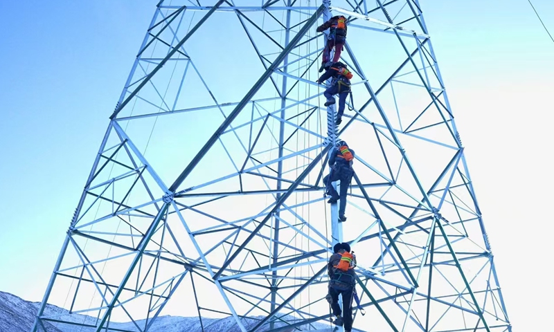 On December 20, 2024, construction workers of State Grid Qinghai Electric Power Company climbed the tower with oxygen tanks on their backs to carry out tower assembly work for the second 330 kV line project in Golog. (Photo by Zou Jianhua)