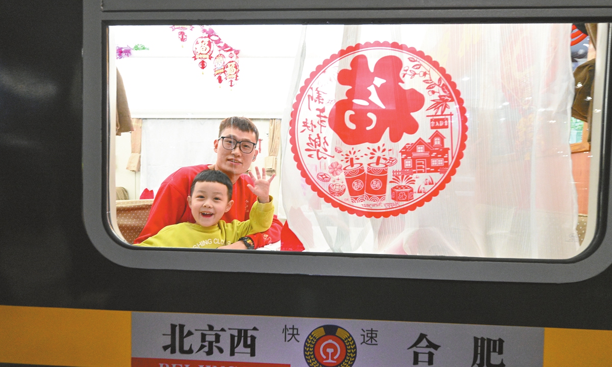 A father and son wave to the camera on train K4159 before it departs from Beijing West Railway Station for Hefei, East China's Anhui Province, on January 14, 2025. Photo: Chen Tao/GT