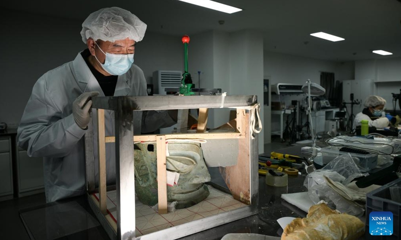 Guo Hanzhong looks at a bronze mask under restoration at Sanxingdui Museum in Guanghan City, southwest China's Sichuan Province, Dec. 18, 2024.