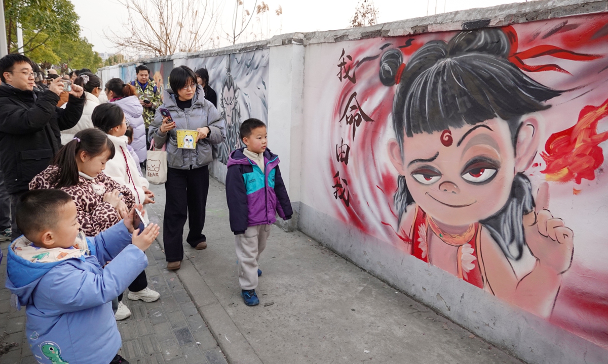 People take photos before a mural of characters from the movie <em>Ne Zha 2</em>in Changzhou, East China's Jiangsu Province, on February 16, 2025. Several 