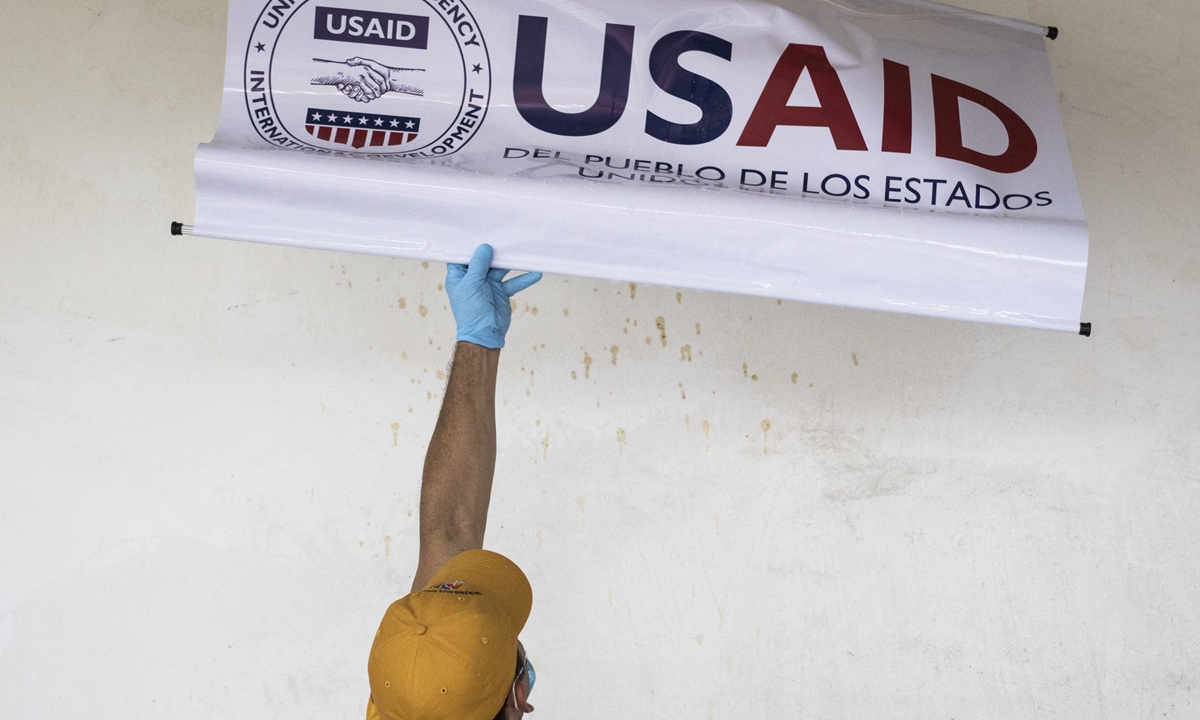 A staff is taking off a sign of the USAID in a community in Cucuta, Colombia, on February 9, 2019. Photo: AFP