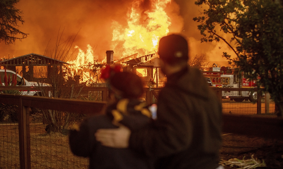 People watch as the Eaton Fire engulfs a structure in Altadena, California, on January 8, 2025. Photo: VCG