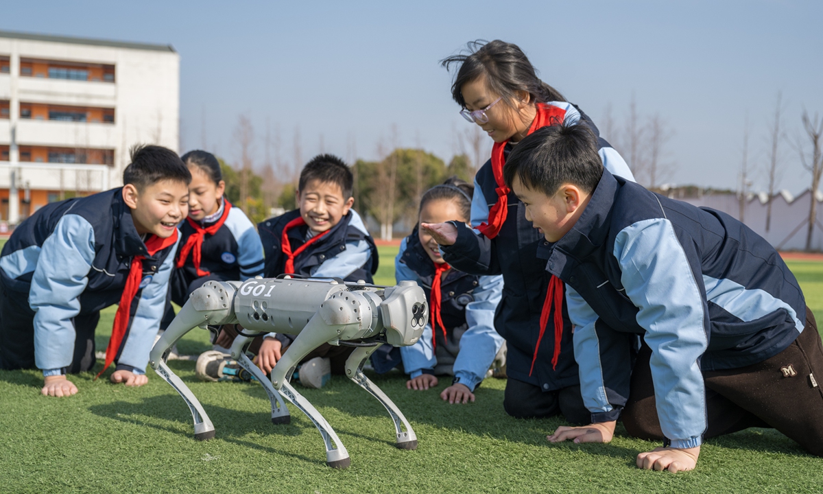 Students interact with a robotic dog during a break at a primary school in Suzhou, Jiangsu Province on February 19, 2025. Photo: VCG